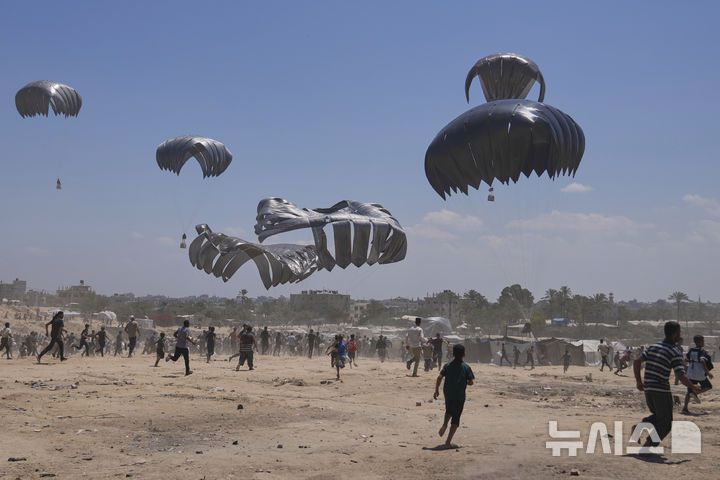 [자와이다=AP/뉴시스] 지난 4일(현지 시간) 가자지구 중부 자와이다에서 팔레스타인 주민들이 낙하산으로 투하되는 인도적 지원 물품을 받기 위해 몰려들고 있다. 2025.08.06.