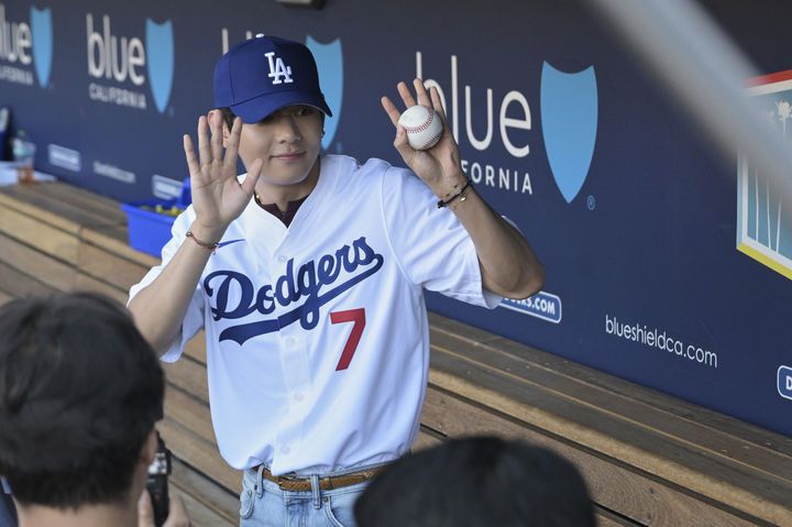 [로스앤젤레스=AP/뉴시스] 방탄소년단(BTS)의 뷔가 25일(현지 시간) 미 캘리포니아주 로스앤젤레스의 다저 스타디움 LA 다저스 더그아웃에서 팬들에게 인사하고 있다. 뷔는 LA 다저스와 신시내티 레즈의 경기 시구자로 나섰다. 2025.08.26.