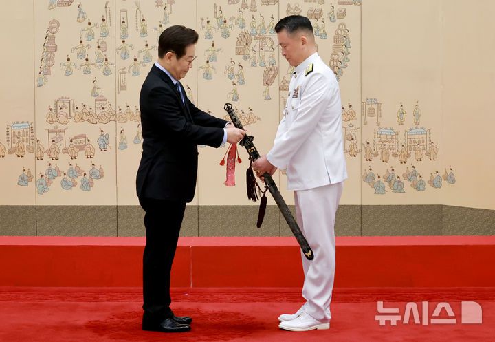 [서울=뉴시스] 최동준 기자 = 이재명 대통령이 2일 서울 용산 대통령실 청사에서 열린 대장 진급·보직 신고 및 삼정검 수치 수여식에서 강동길 해군참모총장의 삼정검에 수치를 달아주고 있다. (대통령실통신사진기자단) 2025.09.02. photocdj@newsis.com