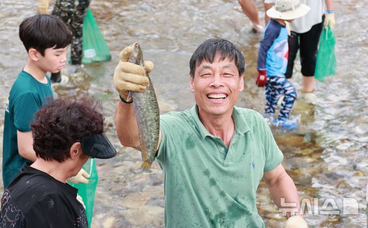 [괴산=뉴시스] 서주영 기자 = 6일 충북 괴산군의 동진천에서 열린 2025 괴산고추축제 프로그램 '고추물고기를 잡아라'의 한 참가자가 잡은 물고기를 들고 웃음을 짓고 있다. (사진= 괴산군 제공) 2025.09.06. photo@newsis.com