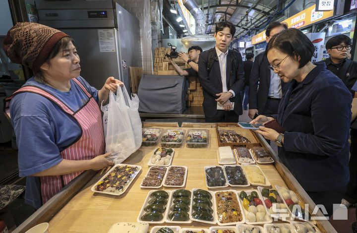 [서울=뉴시스] 정병혁 기자 = 한성숙 중소벤처기업부 장관이 지난 10월 1일 서울 서대문구 영천시장을 찾아 떡을 구매하고 있다. 2025.12.05 jhope@newsis.com