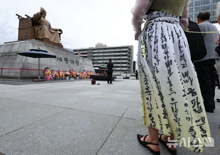 [서울=뉴시스] 최진석 기자 = 579돌 한글날인 9일 오전 서울 광화문광장 세종대왕 동상 앞에서 한 행사 참석자가 한글이 적힌 옷을 입고 있다. 2025.10.09. myjs@newsis.com