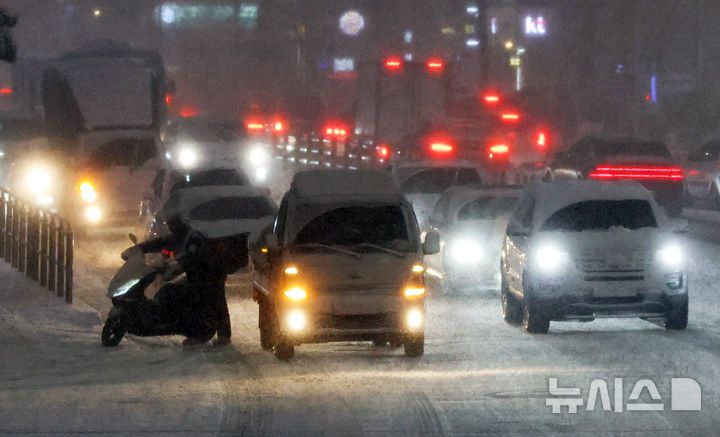 [서울=뉴시스] 최진석 기자 = 서울·인천·경기·강원 대설주의보 발효된 4일 서울 중구 도심 도로에서 한 운전자가 오토바이를 끌고가고 있다. 2025.12.04. myjs@newsis.com