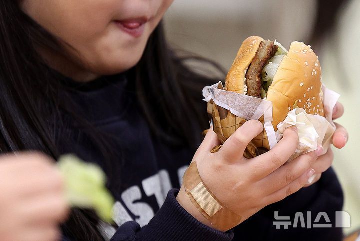 [대구=뉴시스] 이무열 기자 = 전국학교비정규직연대회의의 파업에 따라 대구지역 일부 학교에서 대체식이 제공된 5일 대구 한 초등학교 급식실에서 학생들이 대체식으로 햄버거를 먹고 있다. 2025.12.05. lmy@newsis.com