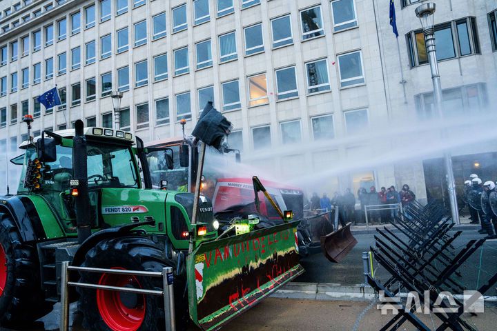 [AP/뉴시스] 18일 유럽연합 정상회의 본부건물 앞 도로를 막는 농부시위대 트랙터에 경찰이 물대포를 쏘고 있다