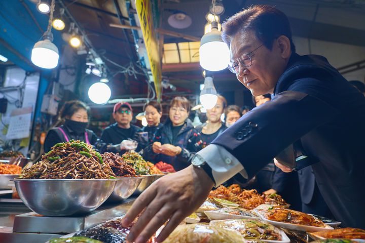 [서울=뉴시스] 이재명 대통령이 23일 부산진구 부전시장을 방문해 반찬을 고르고 있다. (사진=대통령실 제공) 2025.12.23. photo@newsis.com *재판매 및 DB 금지