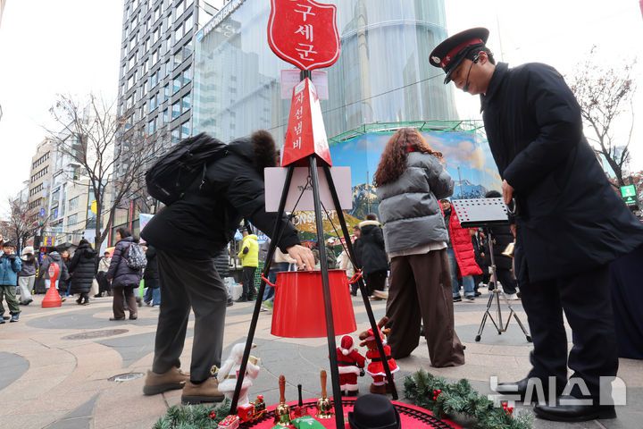[서울=뉴시스] 권창회 기자 = 크리스마스 이브인 24일 오후 서울 중구 명동거리에 놓인 구세군 자선냄비에 한 시민이 성금을 넣고 있다. 2025.12.24. kch0523@newsis.com
