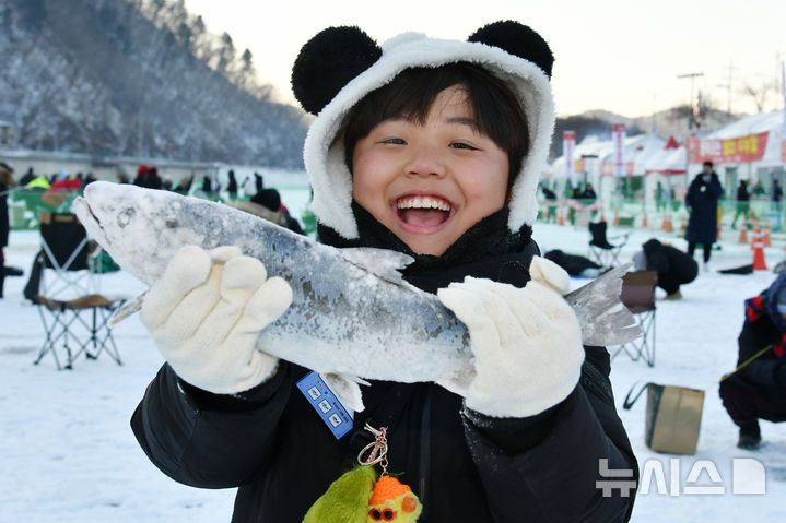 [화천=뉴시스]서백 기자=주말을 맞은 11일 화천산천어축제장을 찾은 한 아이가 얼음낚시터에서 잡은 산천어를 들어 올리며 기뻐하고 있다.(사진=화천군 제공) 2026.01.11. photo@newsis.com