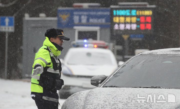 [제주=뉴시스] 우장호 기자 = 제주 산지·중산간·동부·남부에 대설특보가 내려진 11일 오전 제주시 어승생 삼거리 입구에서 제주서부경찰서 소속 경찰관이 도로통제를 하고 있다. 기상청에 따르면 제주도는 12일까지 한라산 등 고지대를 중심으로 최대 15㎝의 눈이 내려 쌓일 것으로 예측됐다. 2026.01.11. woo1223@newsis.com