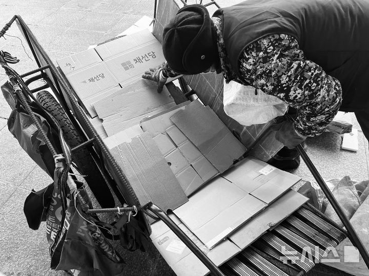 [부산=뉴시스] 이아름 기자 = 박보은(78)씨가 11일 오전 부산 동구의 한 거리에서 자신의 리어카 바닥 위에 폐지를 쌓아 올리고 있다. 2026.01.11. aha@newsis.com