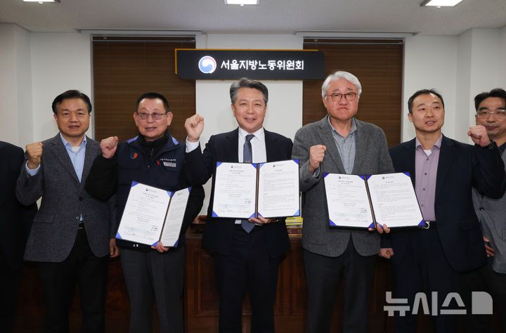 [서울=뉴시스] 황준선 기자 = 지난 14일 밤 서울 영등포구 서울지방노동위원회에서 열린 특별조정위원회 2차 사후 조정회의에서 교섭을 타결한 박점곤 전국자동차노동조합연맹 서울시버스노동조합 위원장과 김정환 서울시버스운송사업조합 이사장이 조정안을 들고 위원들과 기념촬영 하고 있다. 2026.01.15. hwang@newsis.com