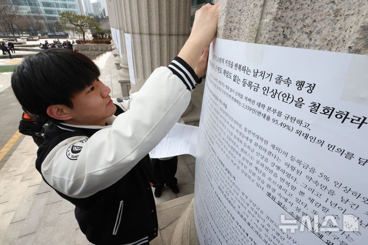[서울=뉴시스] 황준선 기자 = 한국외대 총학생회 소속 학생들이 19일 오후 서울 동대문구 한국외국어대학교에서 학교측의 등록금 인상 계획을 규탄하는 대자보를 붙이고 있다. 2026.01.19. hwang@newsis.com