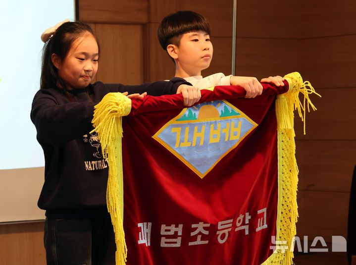 [부산=뉴시스] 하경민 기자 = 부산 사상구 괘법초등학교가 저출산, 학령인구 감소 등으로 인근 학교와 통·폐합이 확정된 가운데 20일 학교 강당에서 열린 이별식에 참석한 학생 대표들이 교기를 반납하고 있다.  1982년 3월5일 28학급(학생 1261명)으로 개교한 괘법초는 지난해 전교생 52명의 소규모 학교로 운영, 인근 감전초등학교와 통·폐합이 확정됐다. 괘법초를 비롯해 올해 부산에서 통·폐합되는 초등학교는 영도구 봉삼초 및 신선초 등 총 3곳이다. 2026.01.20. yulnetphoto@newsis.com