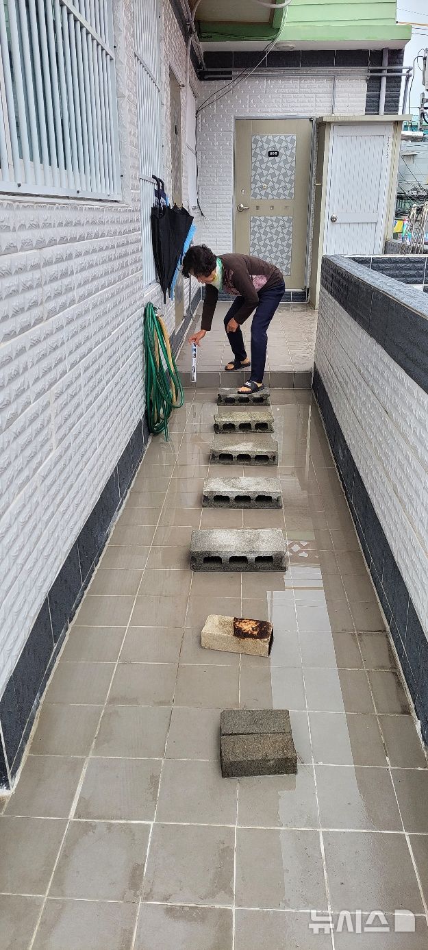 [부산=뉴시스] 진민현 기자 = 지반 침하로 2층 주택 바닥이 기울면서 물이 고여, 사상~하단선 공사 인근 주민이 바닥에 놓인 돌과 블록을 디디며 이동하고 있다. 2026.01.19. truth@newsis.com