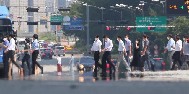 폭염에도 벗을 수 없는 마스크 전국적으로 찜통더위가 계속된 25일 지열로 달아오른 서울 영등포구 여의대로 위로 마스크를 쓴 시민들이 지나고 있다.