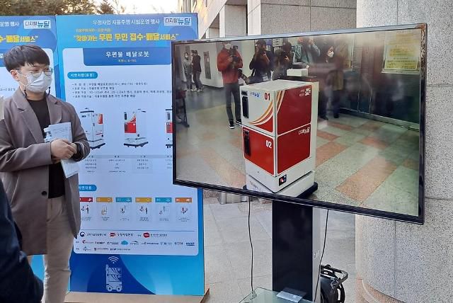 우정사업본부 우정사업 자율주행 시범운영 행사현장에서 시연을 위해 건물에 진입한 우편배달로봇의 작동 과정을 기술 개발업체 관계자가 설명하고 있다.