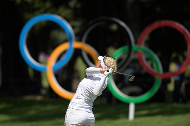 오륜 마크 앞에서 스윙하는 선수.