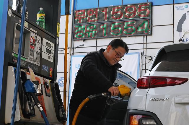 23일 서울 시내의 한 주유소에서 주유하는 시민 뒤로 휘발유와 경유 가격이 표시돼 있다.