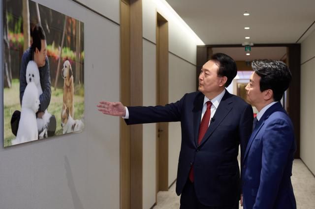 윤석열 대통령이 지난 4일 서울 용산 대통령실 청사에서 가진 KBS '특별대담 대통령실을 가다'에 앞서 박장범 KBS 앵커에게 대통령실 2층 대접견실로 이동하는 복도에 전시된 관저에서 반려견들과 함께 하는 모습 사진을 소개하고 있다. [사진=연합뉴스]