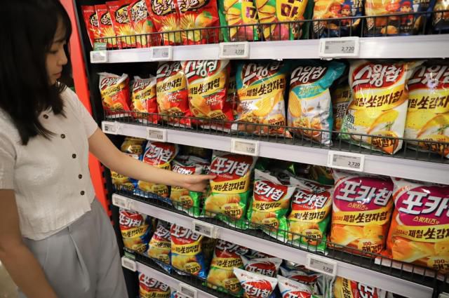 한 소비자가 대형마트에 진열된 오리온 포카칩·스윙칩 제품을 고르는 모습 [사진=오리온]