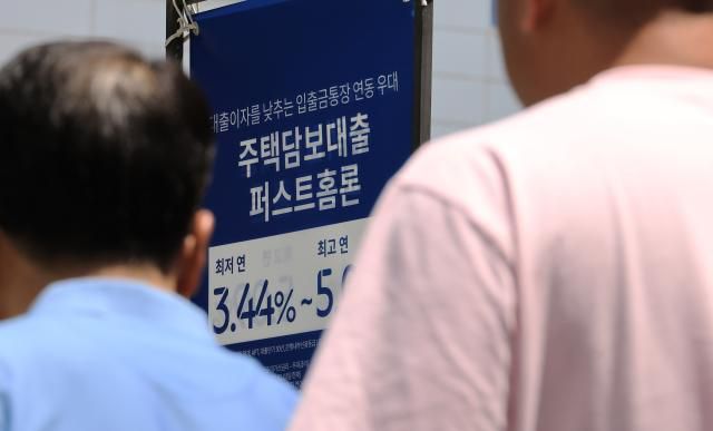 금리 하락 속에 새 정부 출범에 따른 주택·주식 등 자산가격 상승 기대까지 겹쳐 '영끌'(영혼까지 끌어모아 대출) 열기가 좀처럼 식지 않고 있다. 15일 금융권에 따르면 5대 은행(KB국민·신한·하나·우리·NH농협)의 지난 12일 기준 가계대출 잔액은 750조792억원으로, 5월 말(748조812억원)보다 1조9천980억원 불었다. 사진은 15일 서울 시내 은행 앞 대출 홍보물을 지나는 시민. 2025.6.15 [사진=연합뉴스]