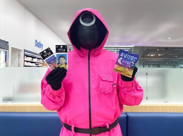 핑크솔져가 GS25에서 선보이는 오징어게임 시즌3 컬래버 상품을 들고 포즈를 취하고 있다. [사진=GS25]