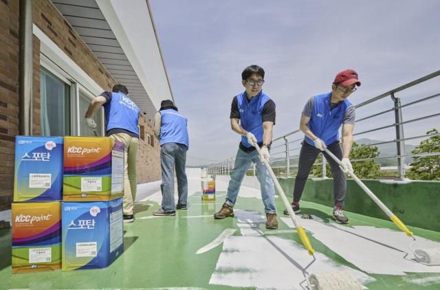 Workers wearing KCC vests coat roof cooling paint/ Courtesy of KCC