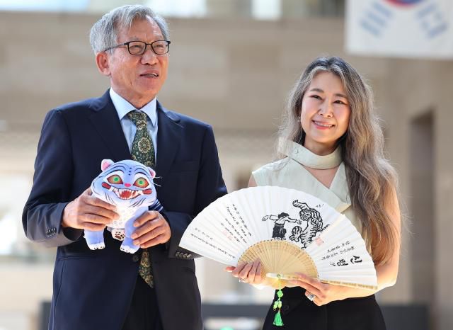 유홍준 국립중앙박물관장(왼쪽)과 넷플릭스 애니메이션 '케이팝 데몬 헌터스'의 매기 강 감독이 21일 서울 용산구 국립중앙박물관에서 선물을 주고 받은 뒤 기념촬영을 하고 있다. [사진=연합뉴스]