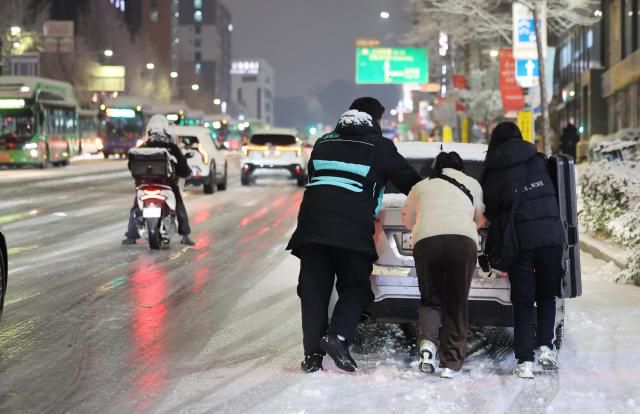 People pushing car in Mapo, Seoul. Dec. 4, 2025 (Yonhap)
