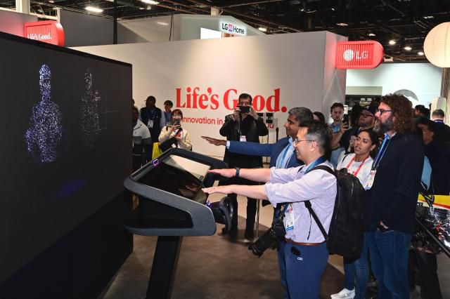 Visitors try out LG Electronics’ AI-powered in-car solutions at CES 2026, where the system analyzes passengers’ gaze to display relevant ads on windows and shows location-based photos tied to personal memories/