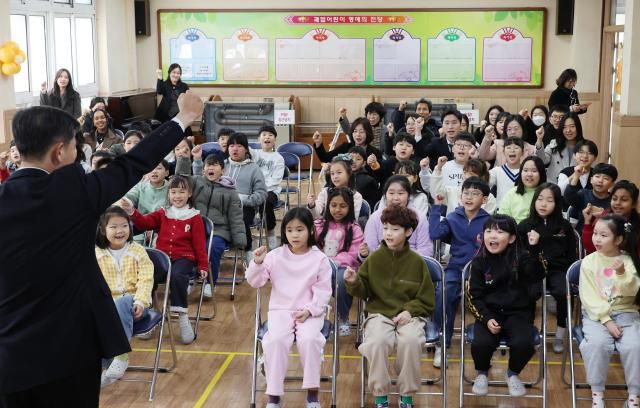 The principal presents a memory album to a student and cheers "Fighting!" during a farewell ceremony at Gwabeop Elementary School in Sasang-gu, Busan, on Jan. 20. Yonhap