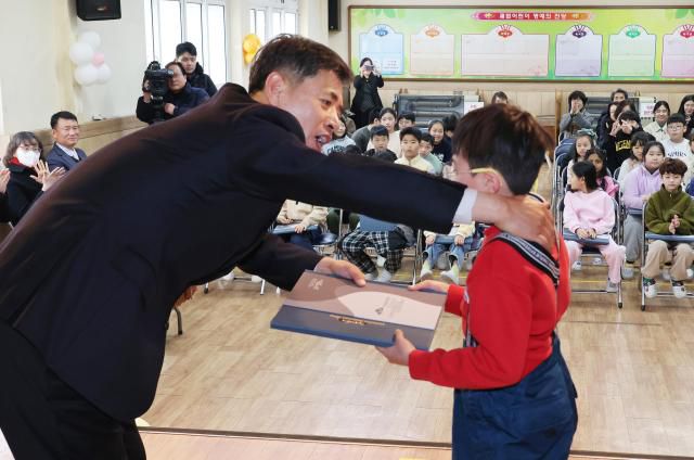 The principal presents a memory album to students during a farewell ceremony at Gwabeop Elementary School in Sasang-gu, Busan, on Jan. 20. Yonhap