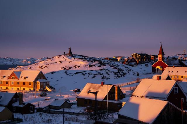 A statue of Hans Egede, a Dano-Norwegian Lutheran missionary, is pictured next to the Cathedral (R) on the top of a hill covered by snow at sunset light in Nuuk, Greenland, on Jan. 21, 2026. AFP-Yonhap