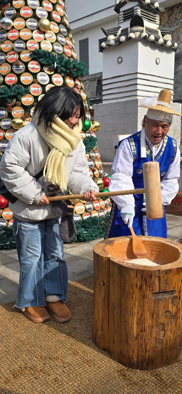 19일 오전 서울 북촌 와이레스(YLESS) 입구에서 한 외국인 여행객이 떡메치기 체험을 하고 있다. [사진=기수정 기자]