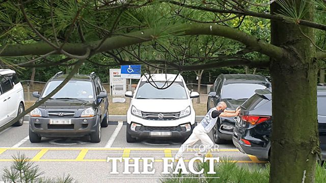 지난달 17일 인천지방법원 후문주차장 장애인 주차구역에서 한 장애인 운전자가 이중 주차된 차량을 직접 밀고 있다. 이러한 배려없는 불법주차로 인해 장애인 운전자들은 고통받고 있다./인천지방법원=남윤호 기자