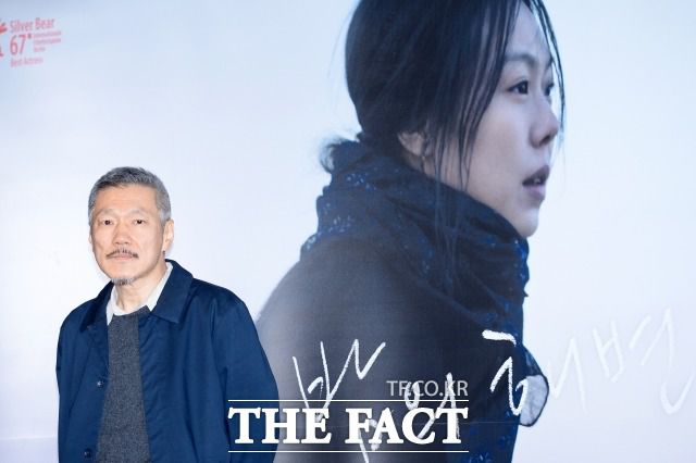 홍상수 감독이 지난 2017년 3월 서울 광진구 롯데시네마 건대입구점에서 열린 영화 '밤의 해변에서 혼자' 언론시사회에 참석해 연인 김민희의 모습이 담긴 포스터 앞에서 포즈를 취하고 있다. /더팩트 DB