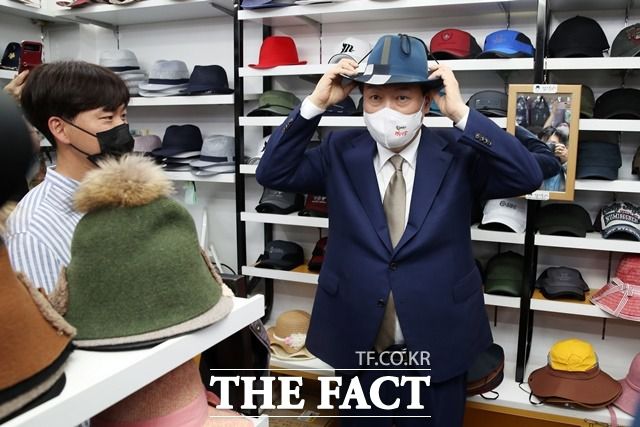 윤석열 대통령이 26일 오후 대구 중구 서문시장 내 모자 점포를 방문해 구입할 모자를 써보고 있다. /뉴시스