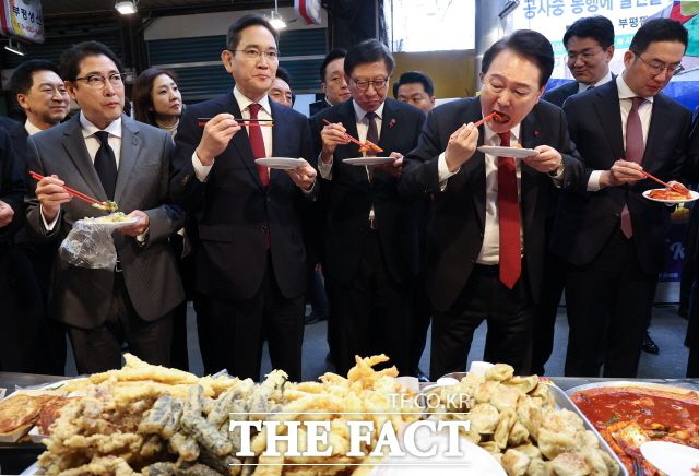 윤석열 대통령이 6일 부산 중구 깡통시장을 방문해 박형준 부산시장, 기업인들과 떡볶이를 시식하고 있다. 왼쪽부터 조현준 효성 그룹 회장, 이재용 삼성전자 회장, 박 시장, 윤 대통령, 구광모 LG그룹 회장. 윤 대통령은 "엑스포 유치했을 때보다 부산을 더 발전시키겠다"고 했다. /뉴시스