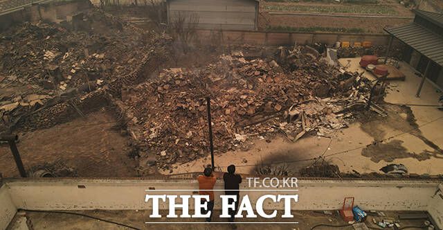 수암리 마을 주민들이 무너진 집을 바라보고 있다.