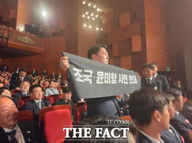 국민의힘 8.22 전당대회에 출마한 안철수 후보가 광복절 경축식 도중 이재명 대통령을 향해 공개 항의에 나섰다. ‘조국·윤미향 사면 반대’라는 문구가 적힌 플래카드를 들고 대통령 경축사 도중 일어선 것이다. /안철수 캠프 제공