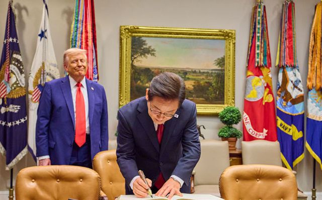 이재명 대통령이 26일 미국 워싱턴DC 백악관에서 트럼프 대통령이 지켜보는 가운데 방명록을 작성하고 있다. /뉴시스
