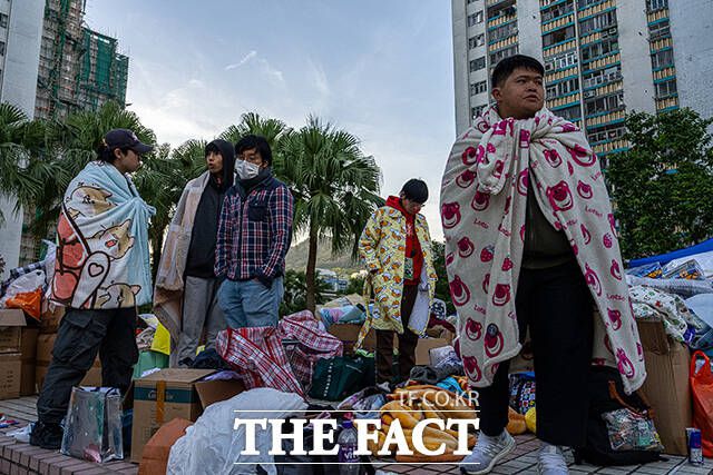 화재 현장 인근 상가 주변에서 주민들이 기부된 물품 속에 서 있다. /홍콩=AP.뉴시스