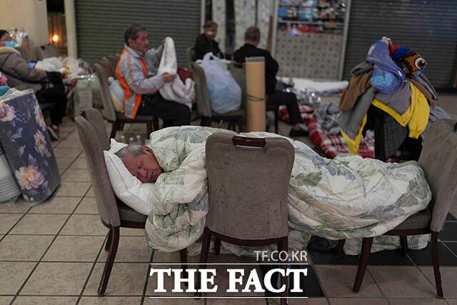 27일(현지시간) 화재 현장 인근 상가 주변에서 한 주민이 의자들을 침대 삼아 잠자고 있다. /홍콩=AP.뉴시스
