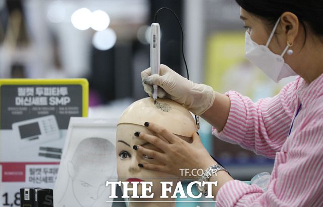 인류는 수천 년간 탈모 치료법을 고민해왔다. 1990년대 후반 탈모 치료제가 개발됐으나 아직 근본적인 치료법을 찾지는 못했다. 사진은 2022년 뷰티박람회에서 진행된 두피 타투 시연. /뉴시스