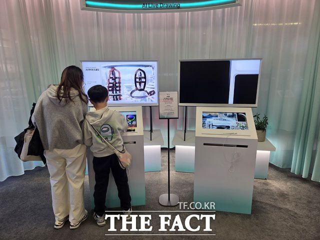 지난 22일 서울 광화문 KT사옥 'KT 온마루' 전시관을 찾은 한 모자 방문객이 대한민국 통신 역사를 체험한 뒤 전시관 내에 설치된 'AI 라이브 드로잉'을 체험하고 있다. /종로=우지수 기자