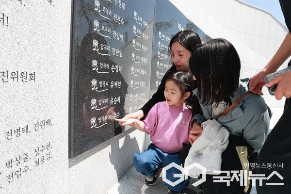 희생자 가족들이 고인의 이름이 새겨진 명판을 쓰다듬고 있다.