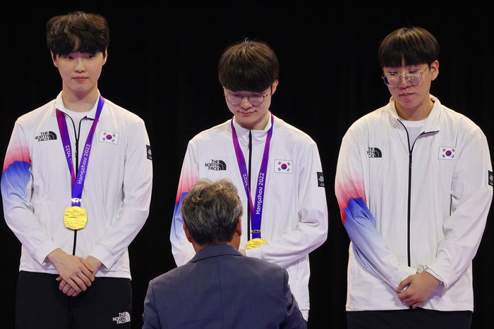 29일 중국 저장성 항저우 e스포츠 센터에서 열린 제19회 항저우 아시안게임 e스포츠 리그 오브 레전드(LoL)에서 금메달을 딴 한국 ‘페이커’ 이상혁이 이기흥 대한체육회장으로부터 금메달을 받고 있다. 왼쪽은 ‘쵸비’ 정지훈, 오른쪽은 ‘룰러’ 박재혁. 사진 | 항저우=연합뉴스