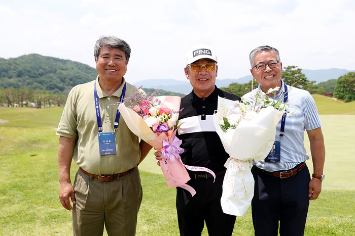 KPGA투어 최다승(43승) 기록 보유자인 최상호(가운데)가 KPGA 선수권대회 2라운드를 마치자 김원섭 회장(오른쪽)과 지태화 수석부회장이 꽃다발을 전달하고 기념촬영하고 있다. 사진 | KPGA