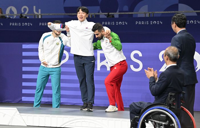 태권도에서 동메달을 획득한 주정훈이 지난달 31일(현지시간) 파리 그랑팔레에서 열린 2024 파리 패럴림픽 태권도 K44 남자 80kg급 시상식에서 다른 메달리스트들의 부축을 받으며 포디움에 오르고 있다. 사진 | 대한장애인체육회