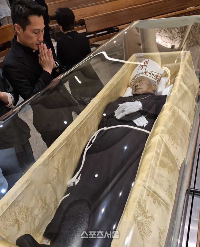 서울 정동 프란치스코 교육회관 성당을 찾은 하철민 안토니오 신부(국군 열쇠성당 주임신부)가 유수일 주교님을 모신 유리관 앞에서 기도하고 있다. 사진 | 이상배 전문기자